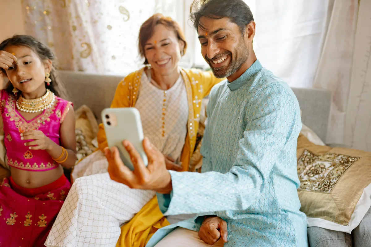 Familie teilt Fotos auf dem Handy als Beispiel für Apps, mit denen Familien in Kontakt bleiben