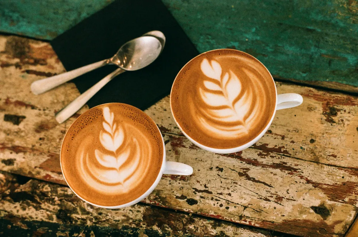 Two cups of coffee side by side on a wooden table