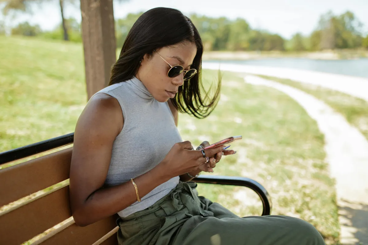 Personne écrivant un message privé sur son téléphone dans un parc, réseaux sociaux vs partage privé