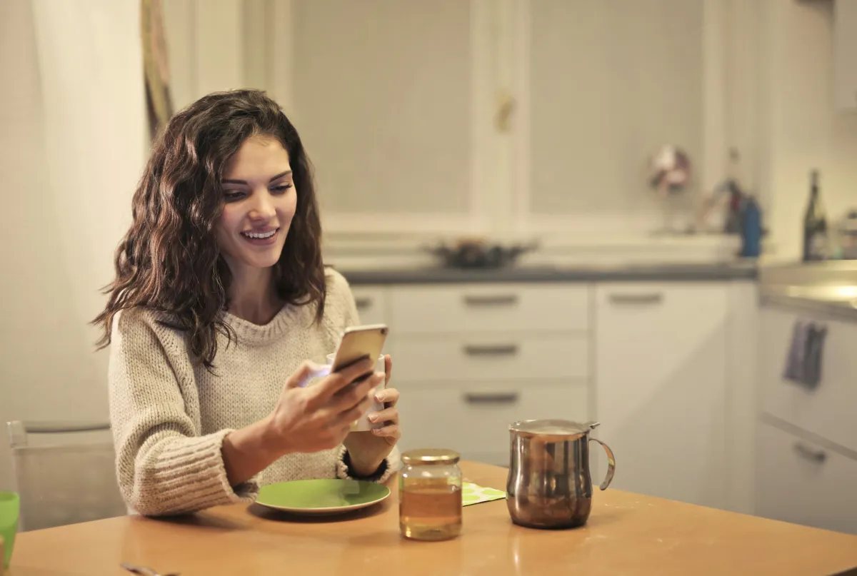 Personne écrivant une pensée sur son téléphone avec un air chaleureux, une pensée par jour dans la relation